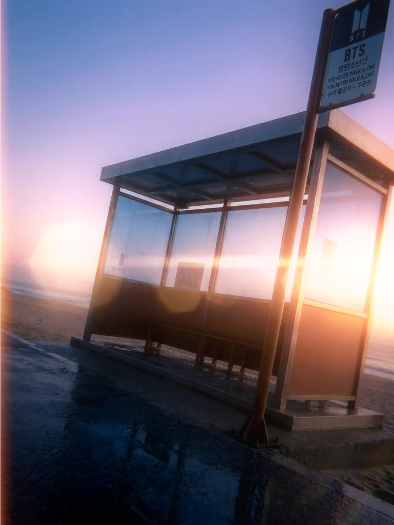 A glass bus shelter in coastal evening light, before and after Dica Y2K processing