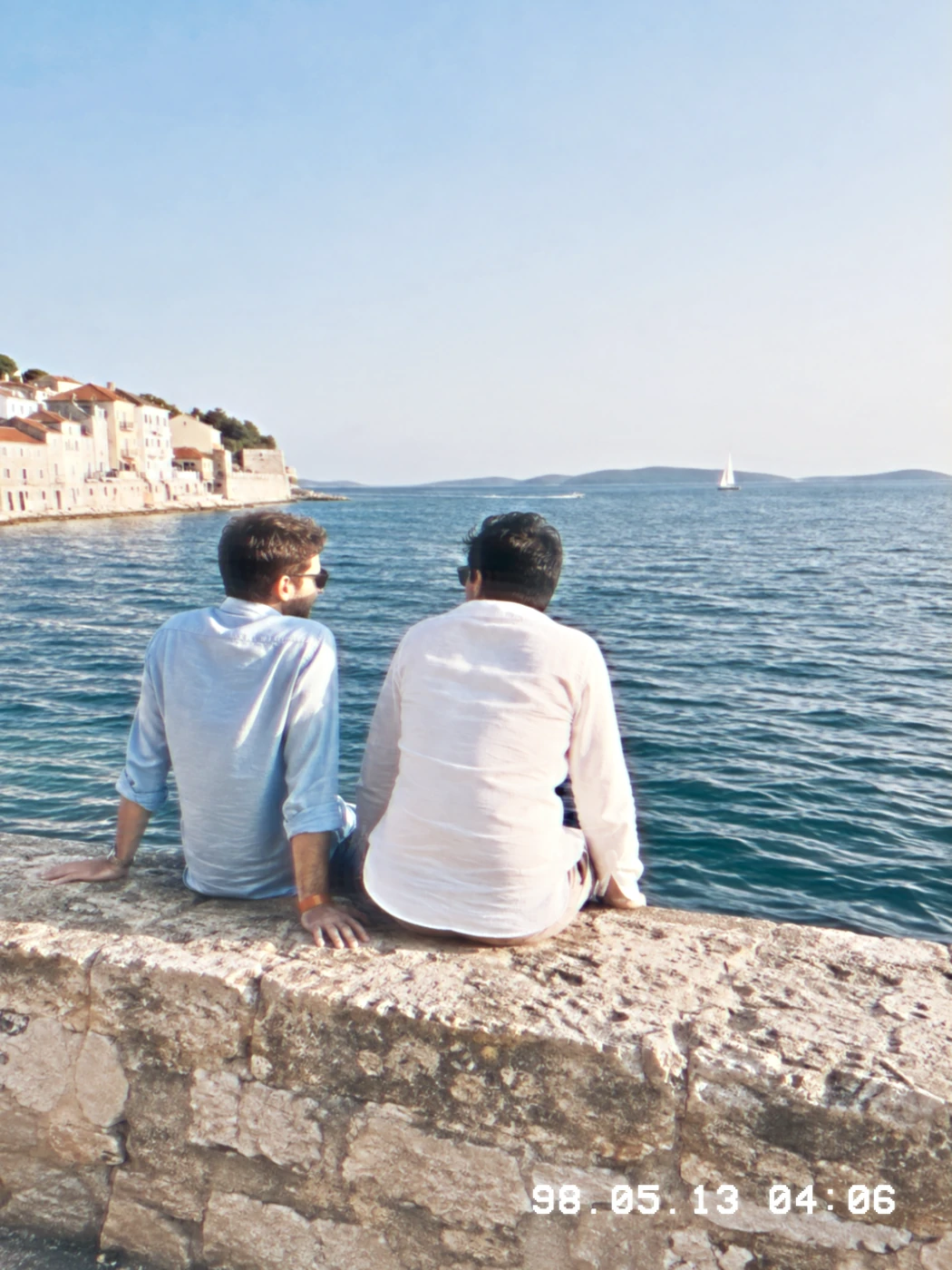An AI-created photograph of two friends by the sea with a camcorder finish and white date stamp